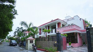 Une maison à deux étages avec un balcon, une entrée fermée par un portail et une moto garée.