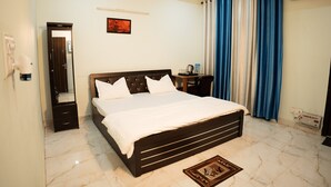Une chambre à coucher comprenant un lit, une commode, un miroir, un bureau et un climatiseur fixé au mur.