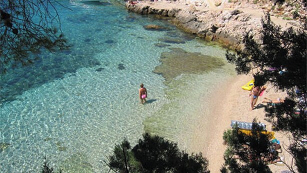 A beach with clear water, rocky shore, and people sunbathing. - Superior apartment in Stari Grad (Stari Grad)