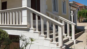 A two-story building with a white exterior, a balcony with white balustrades, and a red-tiled roof. - Superior apartment in Stari Grad (Stari Grad)