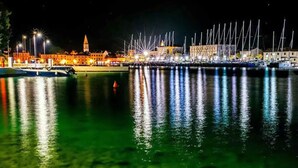 A marina at night with boats docked, a waterfront promenade, and illuminated buildings. - Comfortable apartment in Stari Grad (Stari Grad)