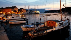 A marina with several boats docked, a building with lights in the background, and calm water reflecting the boats. - Comfortable apartment in Stari Grad (Stari Grad)