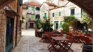 An outdoor café area with stone flooring and wooden tables and chairs. - Comfortable apartment in Stari Grad (Stari Grad)