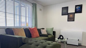 A living room with a sectional sofa, a small table, and a radiator. There are three framed artworks on the wall. - Edgbaston Birmingham Apartment (Birmingham)