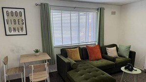 A modern living room with a green sofa, a small table, and a chair. - Edgbaston Birmingham Apartment (Birmingham)