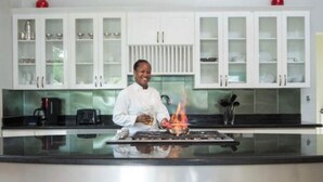 A modern kitchen with white cabinets, a stainless steel countertop, and a central island with a gas stove. - Hospitality Expert - Little Waters Villa Negril (Negril)