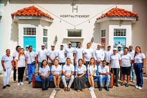 A group of people in front of a building with a sign reading "HOSPITALITYEXPERT".