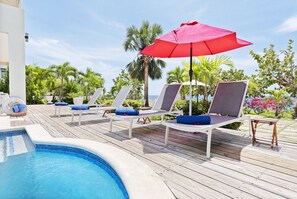 A poolside area with lounge chairs and a red umbrella. - Hospitality Expert - Little Waters Villa Negril (Negril)