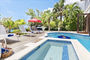 A pool area with lounge chairs, a hot tub, and a wooden deck.