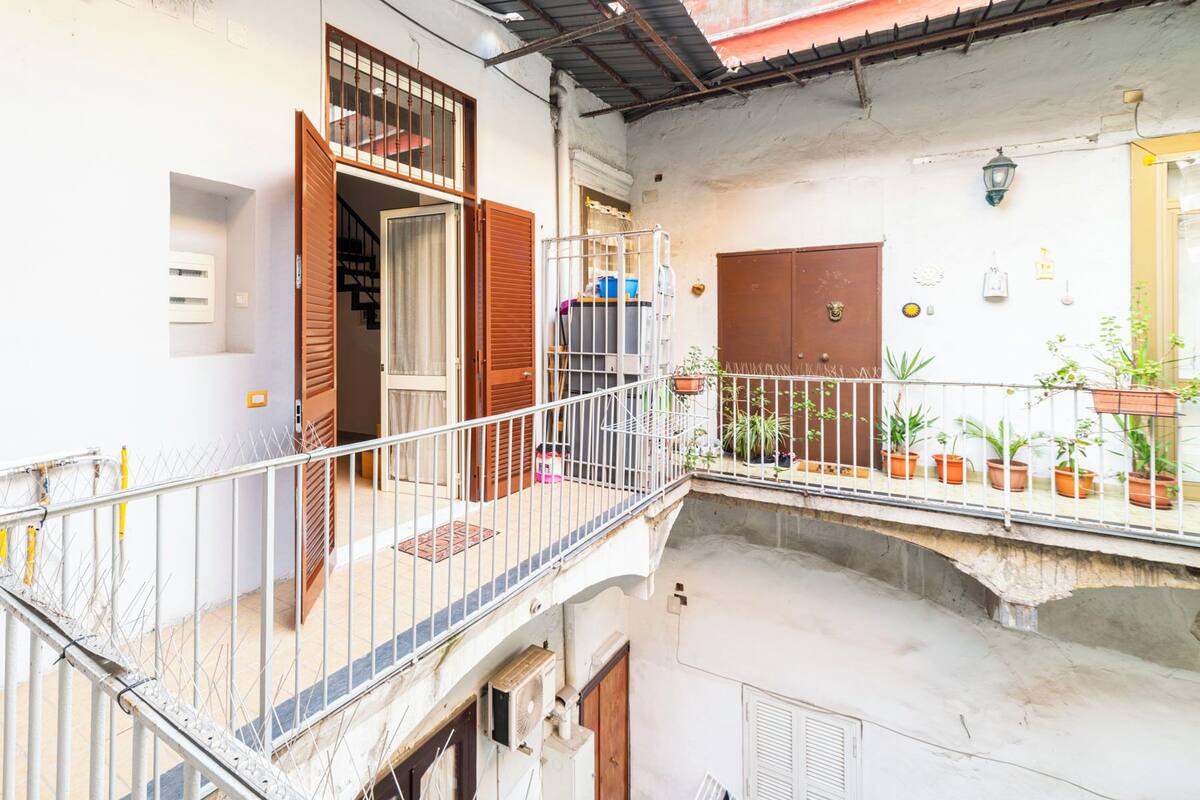 A multi-level residential building with a balcony, a staircase, and a door with a window.