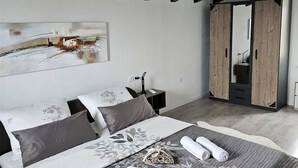 A modern bedroom with a large bed, a wardrobe, and a painting on the wall. - Cool 3-bedroom house with AC in charming Praputnjak (Hreljin)