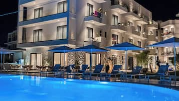 Un hôtel moderne doté d’une piscine, de chaises longues et de parasols.
