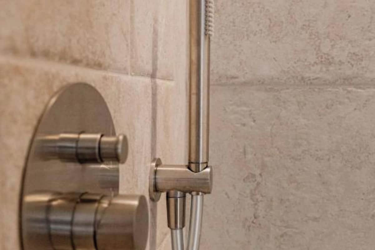 A modern shower control with a handheld showerhead and a handheld faucet.