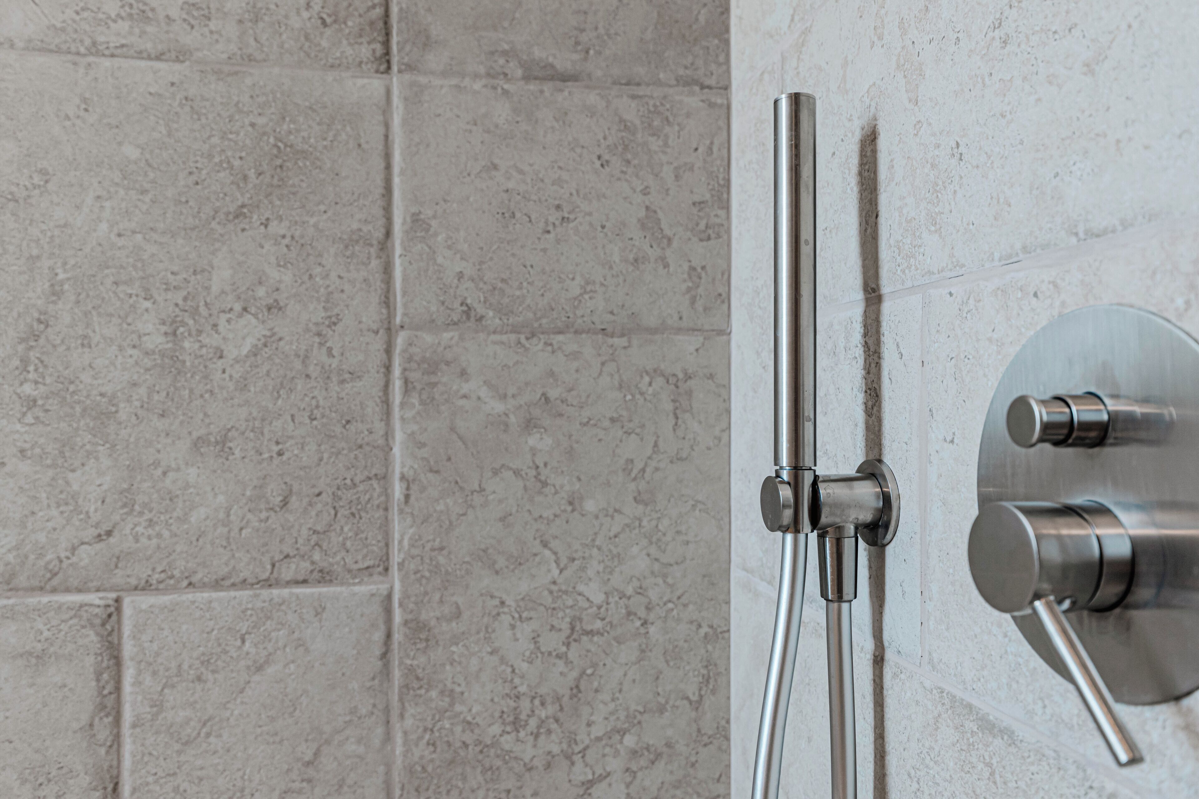 A shower with a modern design, featuring a wall-mounted control panel and a handheld showerhead.