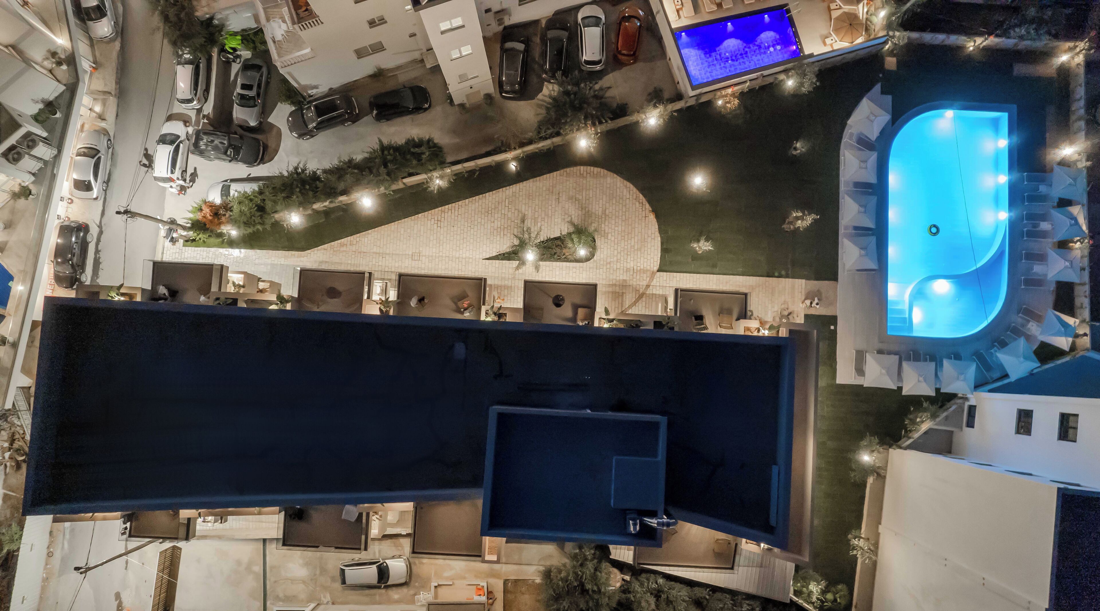Vista aérea de un hotel con piscina, varios espacios de estacionamiento y una terraza en la azotea.
