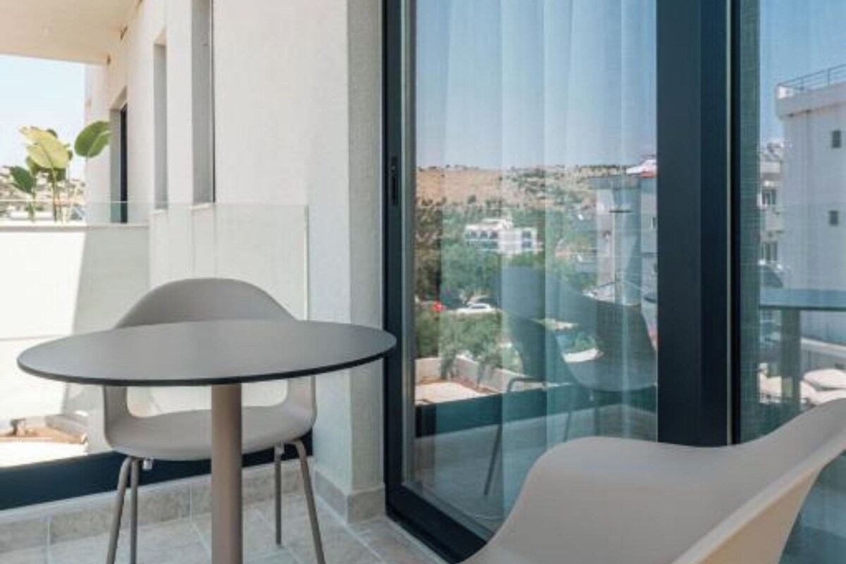 A modern balcony with a glass door, a round table, and a single white chair.