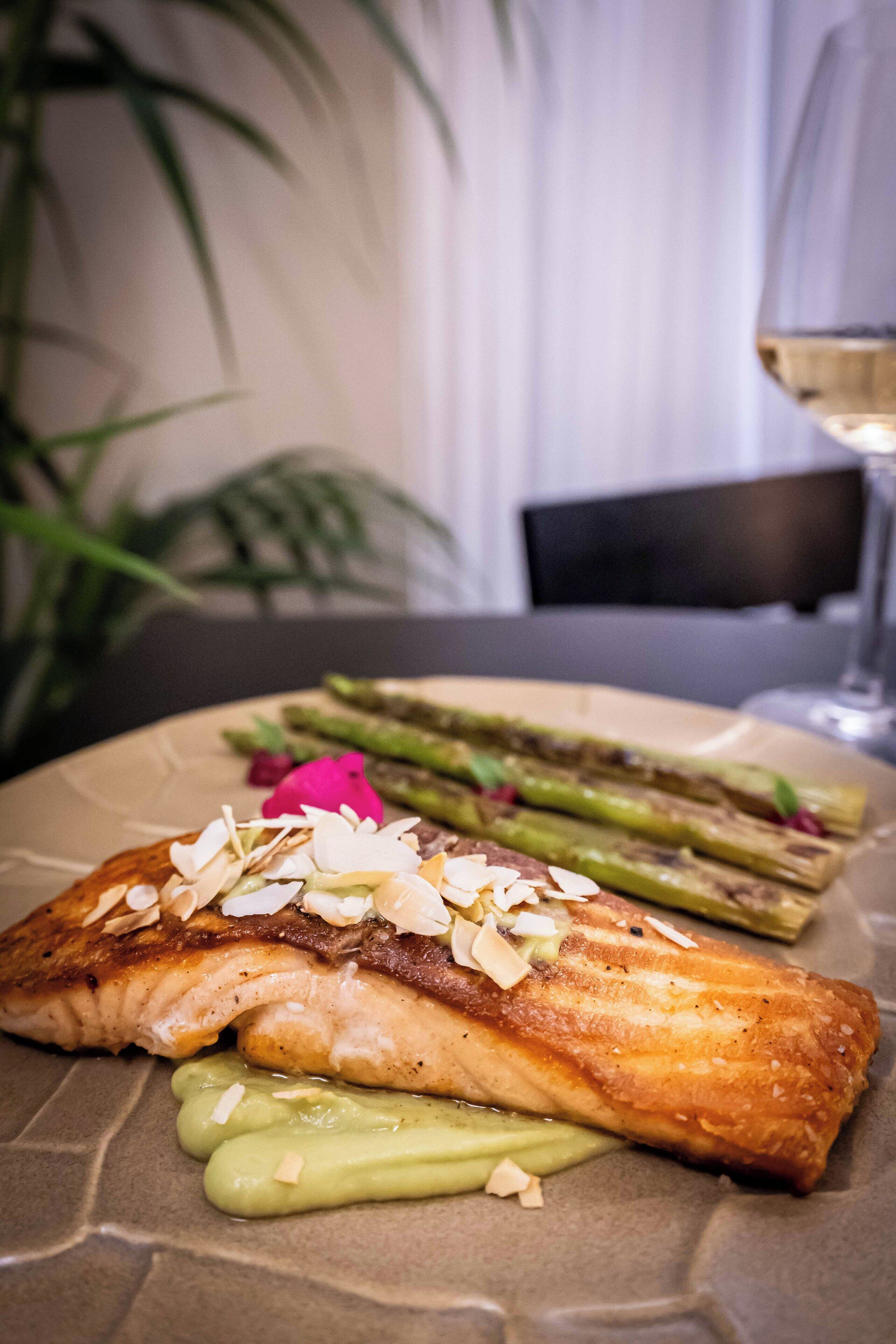 A plate with a piece of salmon, asparagus, and a dollop of green sauce.