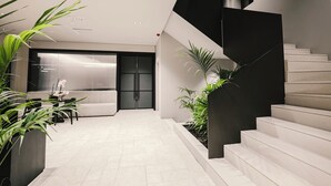 A modern interior with a staircase, a seating area, and potted plants. - Sondor Hotel (Ksamil)