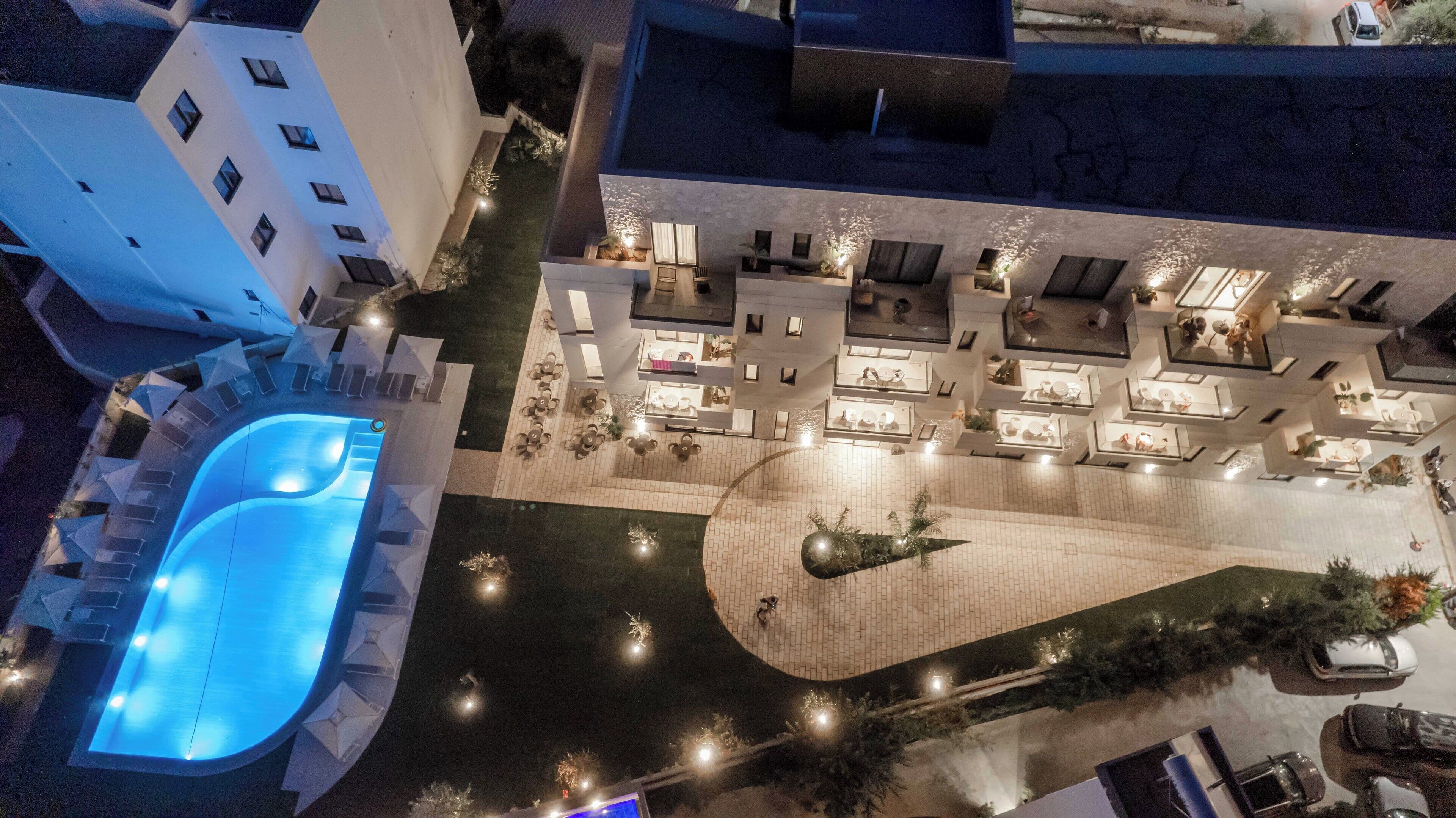 An aerial view of a hotel with a swimming pool, outdoor seating areas, and a landscaped courtyard.