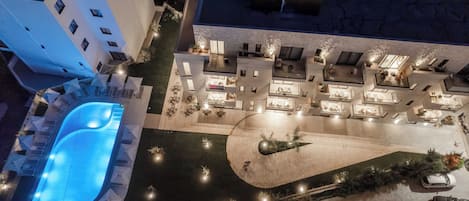 An aerial view of a hotel with a swimming pool, outdoor seating areas, and a landscaped courtyard.