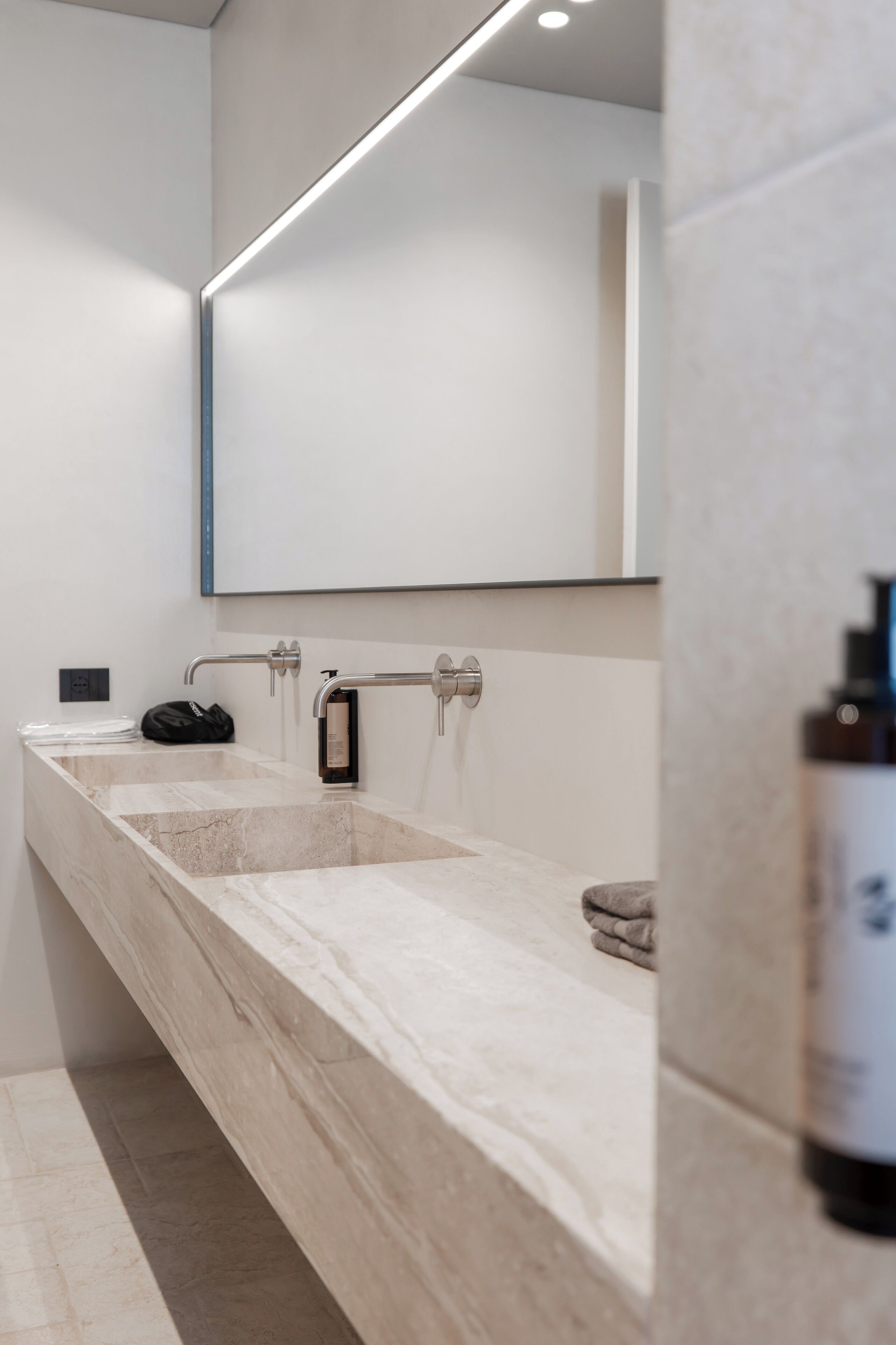 Un baño moderno con un lavamanos grande de mármol, un espejo y un perchero para toallas.