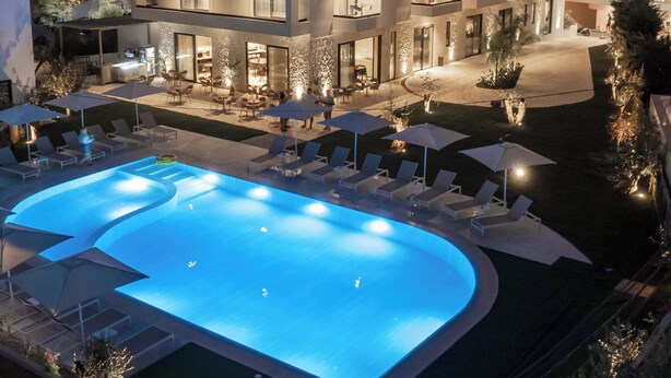 A multi-story hotel with a swimming pool, outdoor seating, and a well-lit courtyard. - Sondor Hotel (Ksamil)