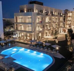 A multi-story hotel with a swimming pool, outdoor seating, and a well-lit courtyard.