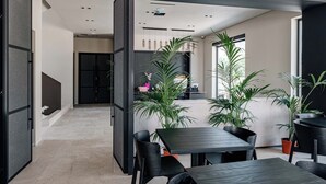 A modern interior with a dining area, kitchen, and a view of the outside. - Sondor Hotel (Ksamil)