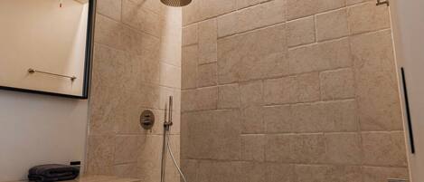 A modern bathroom with a shower, a marble sink, and a wall-mounted mirror.