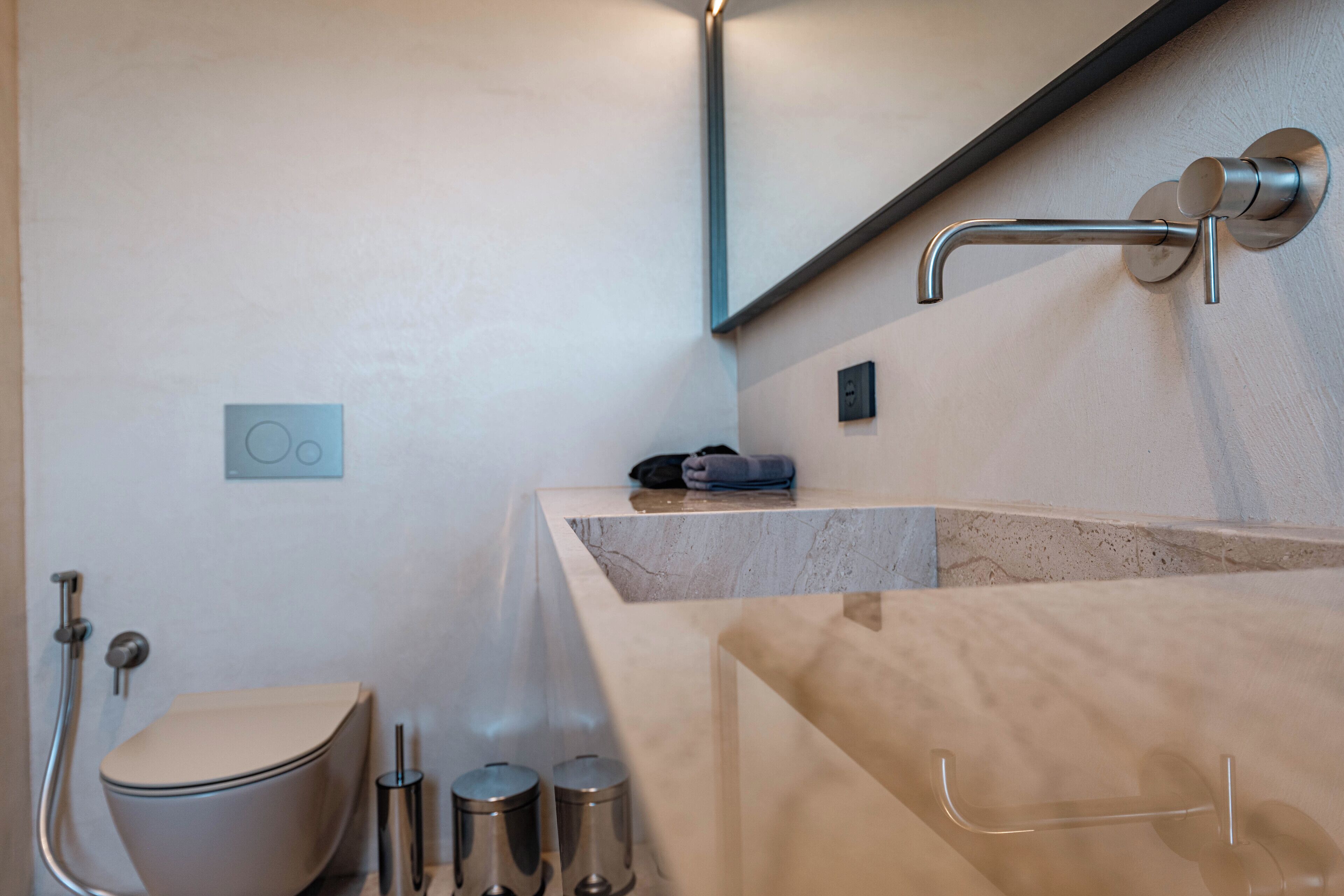 A modern bathroom with a toilet, bidet, and a marble sink with a towel rack.