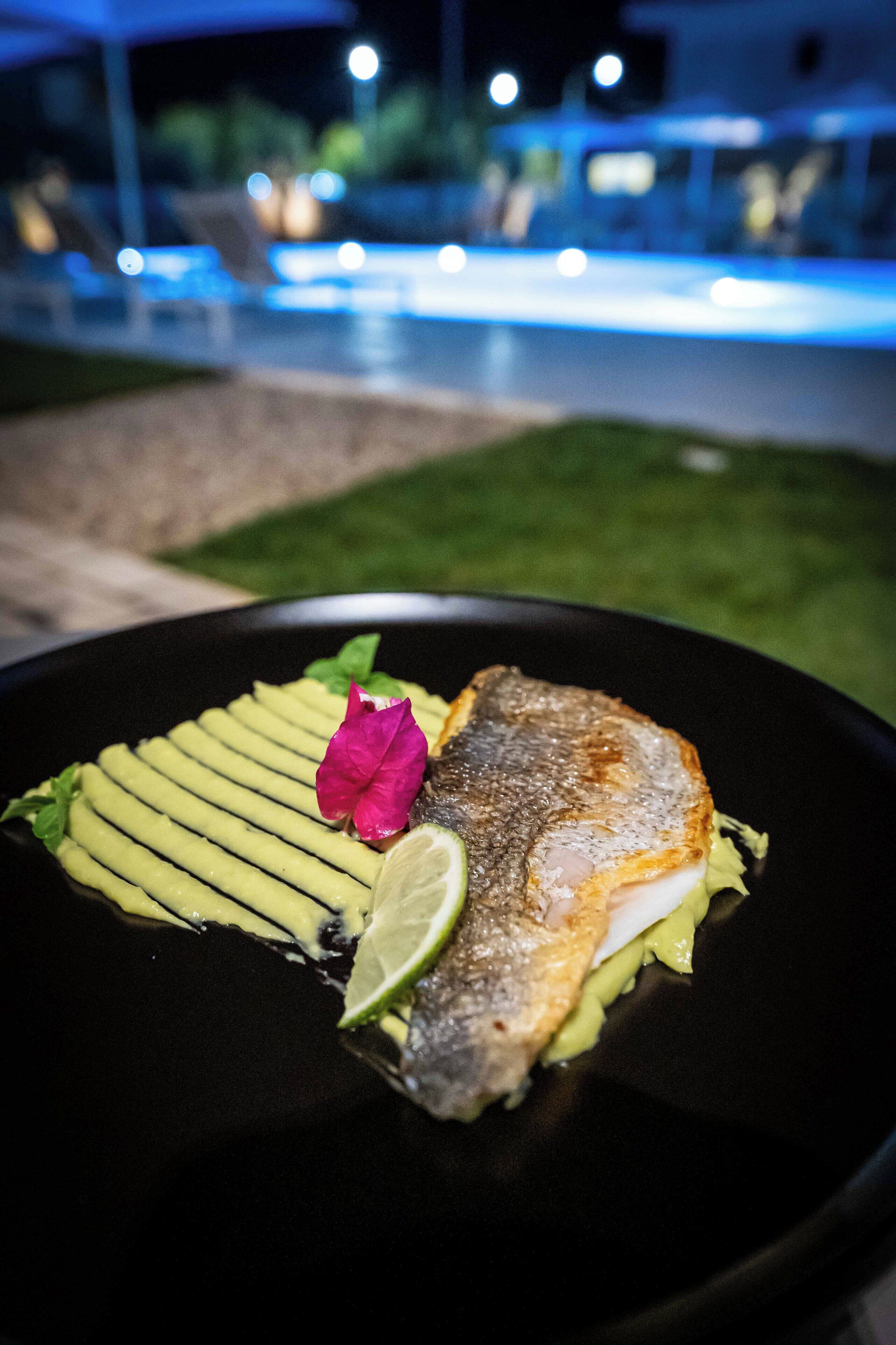 Un plat composé de poisson et d’avocat, servi dans une assiette noire.