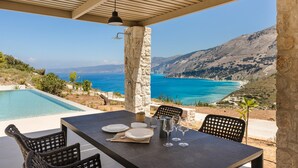 A dining area with a table set for four, overlooking a pool and a scenic mountain view. - Electra Zolla Villa (Zola Village)