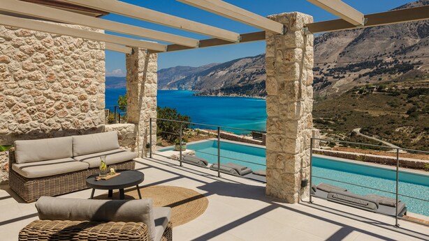 A balcony with a stone wall, a wicker sofa, a small table, and a pool with a view of the sea and mountains. - Electra Zolla Villa (Zola Village)