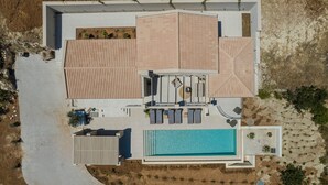 An aerial view of a modern house with a swimming pool, a covered patio, and a garden area. - Electra Zolla Villa (Zola Village)