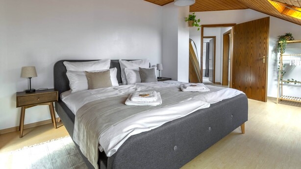 Une chambre moderne avec un grand lit, une tête de lit en bois, des tables de chevet et un ventilateur de plafond.
