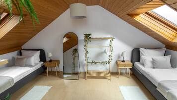 Un dormitorio con dos camas, un tragaluz, un espejo y una estantería de madera con plantas.