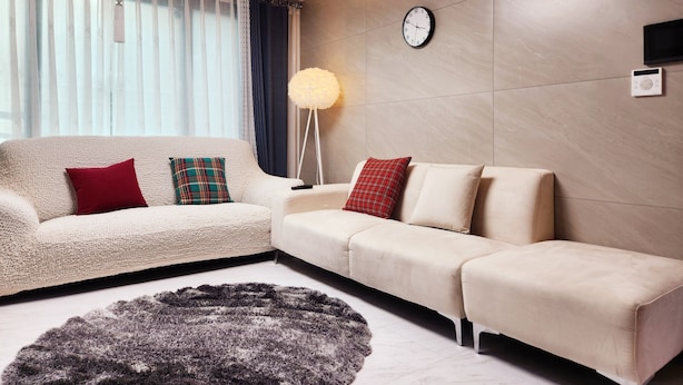 Ein modernes Wohnzimmer mit einer Couch, einem Teppich, einer Stehlampe und einer Wanduhr.