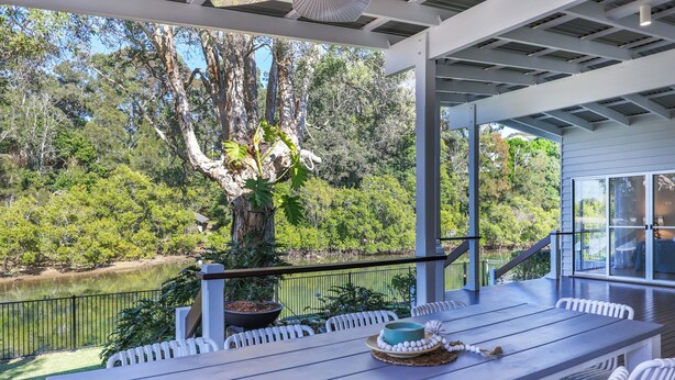 Un espacio de comedor al aire libre con techo y vistas a un lago y árboles.