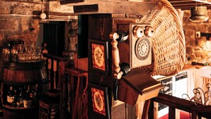 A rustic interior with exposed wooden beams, a vintage rotary phone, and a wicker basket.