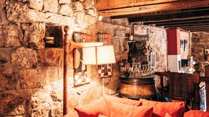 A cozy room with a stone wall, wooden ceiling, and a red sofa.