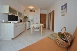 Un espacio habitable compacto con kitchenette, comedor y sofá.