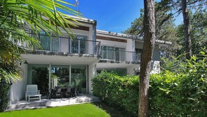 A modern two-story house with a balcony, large windows, and a well-maintained garden.