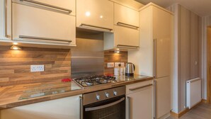 A modern kitchen with wooden flooring, stainless steel appliances, and a built-in oven. - Coastal Aprt in Anstruther -sleeps4 -Tv - Wifi (Anstruther)
