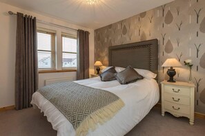 A bedroom with a large bed, a nightstand with a lamp, and a window with curtains. - Coastal Aprt in Anstruther -sleeps4 -Tv - Wifi (Anstruther)