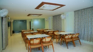 A dining area with multiple tables and chairs, ceiling fans, and recessed lighting.