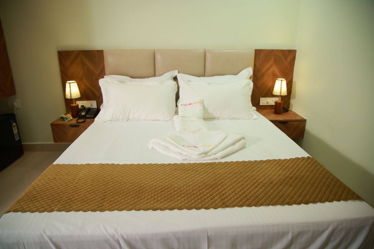 A hotel room with a large bed, two bedside lamps, and a wooden headboard.