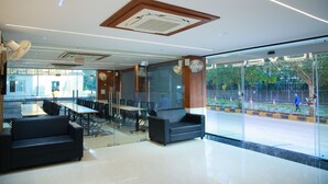 A modern indoor space with a glass partition, a sofa, a table, and chairs.