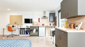 A modern kitchen with a dishwasher, oven, and a small dining area. - Student Only The Towpath (Chester)