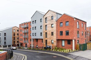 A modern multi-story residential building with a mix of brick and metal facades, a reception area, and a gated entrance.