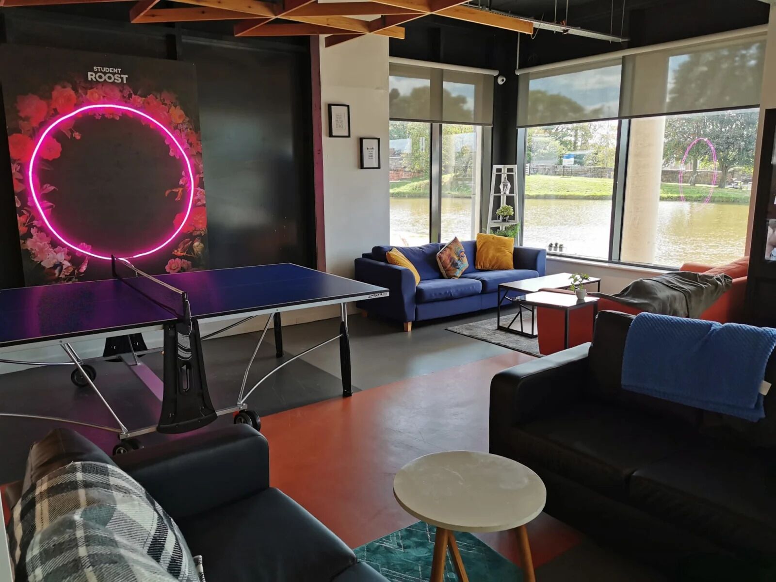 A modern room with a ping pong table, a blue sofa, and a view of a lake.